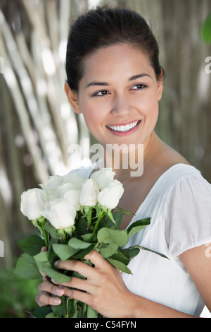 Young woman holding bunch of white flowers and smiling