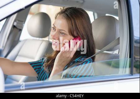 Beautiful young woman talking over mobile phone while driving a car Stock Photo