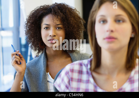 Two women sitting in classroom with focus on African American woman Stock Photo
