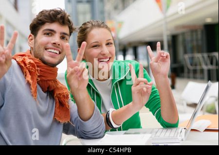 Portrait of friends gesturing peace while using laptop Stock Photo