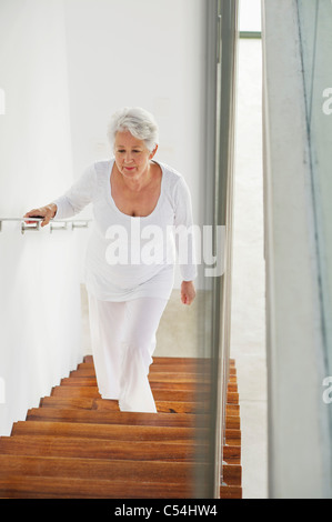 High angle view of a senior woman moving up staircases Stock Photo