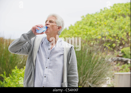 Thirsty senior man drinking water Stock Photo