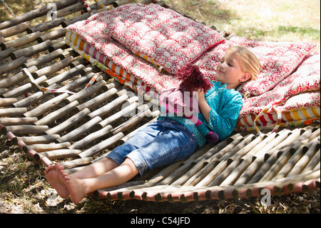 Little girl playing with toy while lying in hammock