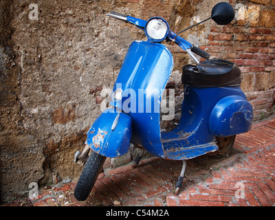 Typical italian retro style scooter parked in front of a brick wall. Stock Photo