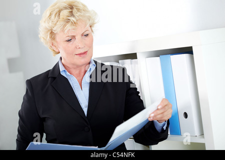 Portrait of middle aged businesswoman reading paper in office Stock Photo