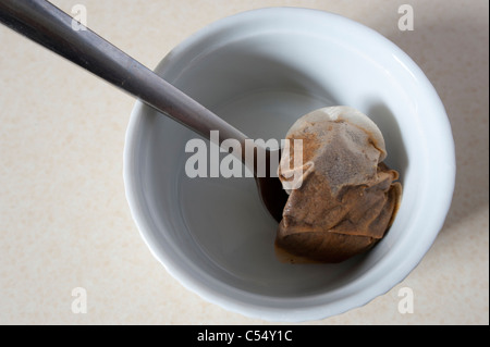 Used tea bag in a white dish with a teaspoon. Stock Photo