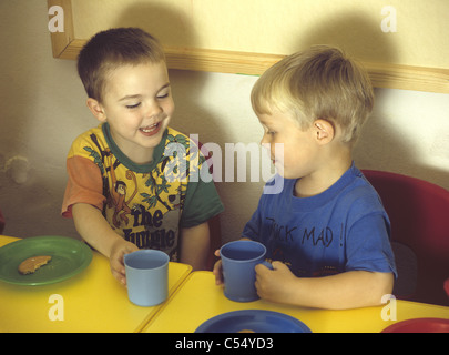 Two happy young boys at preschool with a drink, enjoying snack time, U.K. UK Stock Photo