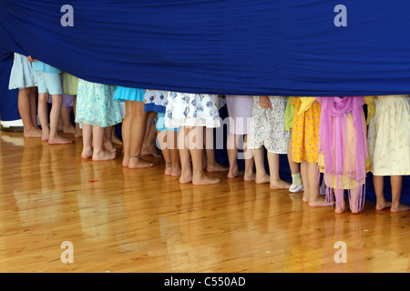 Children hiding behind a blue curtain
