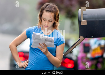 Teenage Girl reading the mail by the mailbox. Stock Photo