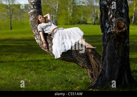 outdoor portrait of beautiful hippie girl lying on birch tree. forest on background Stock Photo