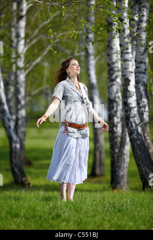 outdoor portrait of beautiful hippie girl on green grass in birch forest Stock Photo