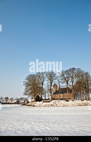 The Netherlands, Hijum, Church on mound in snow. Stock Photo