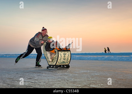 The Netherlands, Hindeloopen, the Dutch capital of skating culture. Man on skates pushing antique sledge. Stock Photo