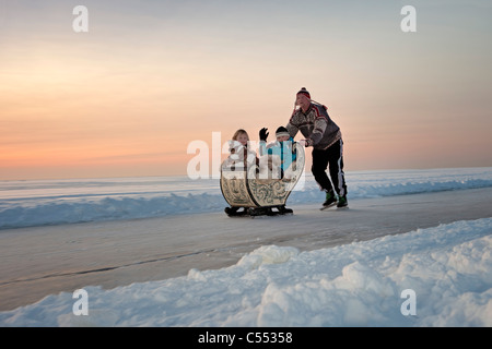 The Netherlands, Hindeloopen, the Dutch capital of skating culture. Man on skates pushing antique sledge. Sunset. Stock Photo