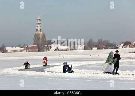 Dutch capital of skating culture. People in traditional dress, figure scating, sledging with prickers, and skating with sledge. Stock Photo