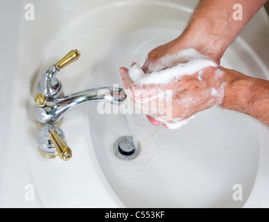 Washing hands in a bathroom sink Stock Photo