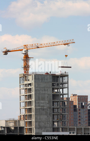 Construction. Building site. Yellow construction crane, an unfinished concrete house on the skyline Stock Photo