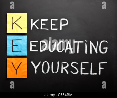 KEY acronym - KEEP EDUCATING YOURSELF. Educational concept with color sticky notes and white chalk handwriting on a blackboard. Stock Photo