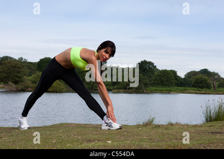 A young latino woman performs a yoga stretch in Richmond Park, London. Stock Photo