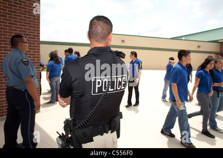 Policeman at high school in Pharr, Texas, monitors students walking through courtyard between classes Stock Photo