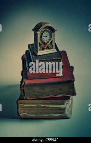 Old fashioned clock over a pile of books Stock Photo