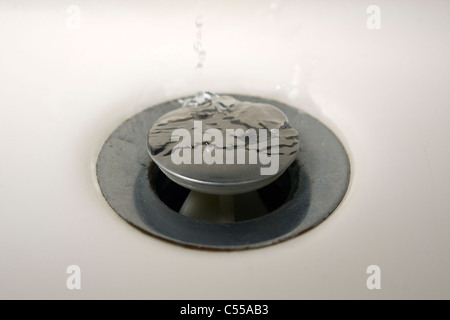 Ripples made by water dripping on a drain plug in a bathroom sink Stock Photo