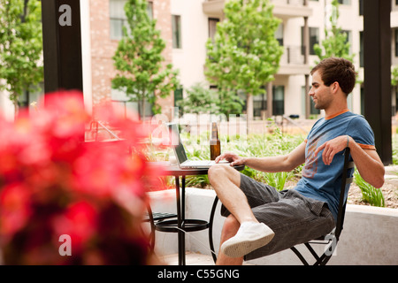 Young man using a laptop and having beer Stock Photo
