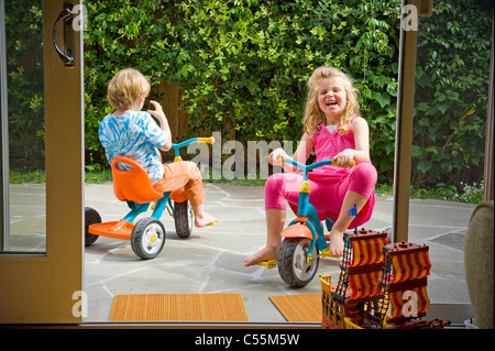 Boy and his sister riding tricycles Stock Photo