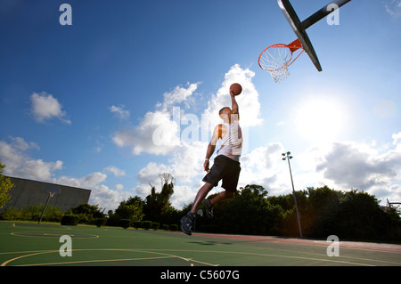 Slam dunk. Dynamic image of male basketball player throwing ball in a ...