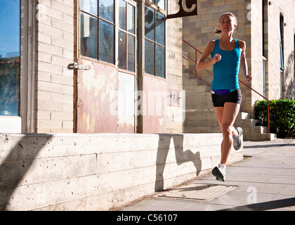 Female athlete running on sidewalk, Midtown, San Diego, California, USA Stock Photo