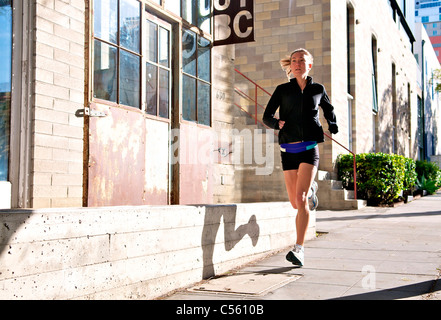 Female athlete running on sidewalk, Midtown, San Diego, California, USA Stock Photo