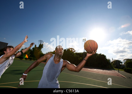 males playing outdoor basketball game Stock Photo