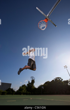 Slam dunk. Dynamic image of male basketball player throwing ball in a ...