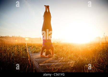 Mid adult woman doing morning yoga in a field, Upper Herring Lake Nature Preserve, Frankfort, Benzie County, Michigan, USA Stock Photo