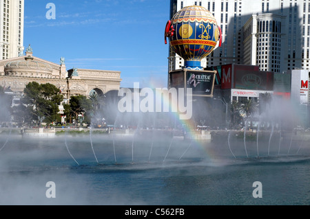 a rainbow appears in the mist of the Bellagio fountain on the Las Vegas Strip. Across the strip is the Paris Las Vegas sign. Stock Photo