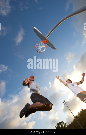 male scoring during outdoor basketball game, upward angle toward goal Stock Photo