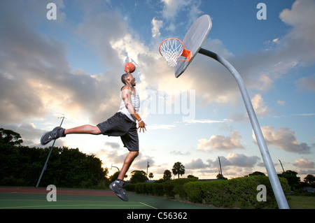 male making slam dunk at outdoor basketball goal Stock Photo