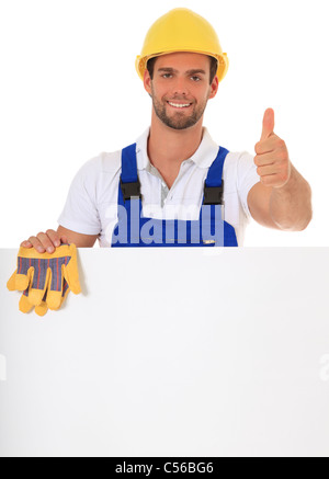 Manual worker behind white wall showing thumbs up. All on white background. Stock Photo