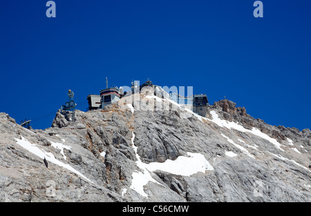 View from Zugspitze glacier plateau to the summit of Zugspitze. Cable car station,  restaurants, observation decks, golden cross Stock Photo