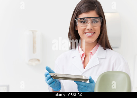 Smiling beautiful dentist holding tray of dental instruments Stock Photo