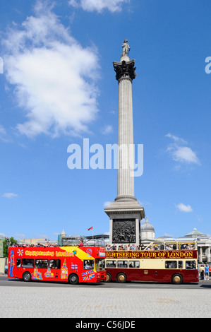 London street scene tourists on double decker open top sightseeing tour buses pass Nelsons Column blue sky summer day in Trafalgar Square England UK Stock Photo