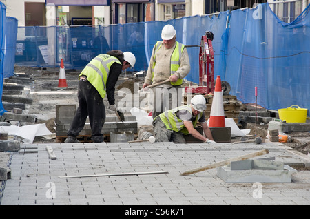 High Street, Bangor, Gwynedd, North Wales, UK. Council workmen digging up the road replacing paving stones in the precinct Stock Photo