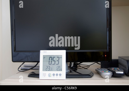Close up of Owl electricity power monitor against a flat screen TV with standby red light on Stock Photo