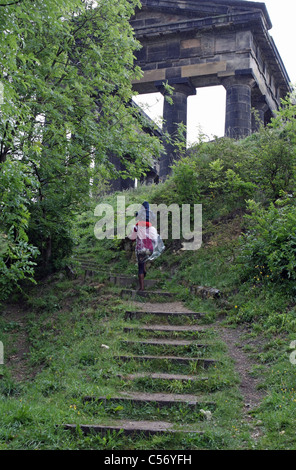 A lady, with her child sitting on her shoulders, walking up stone steps to the Penshaw monument Stock Photo