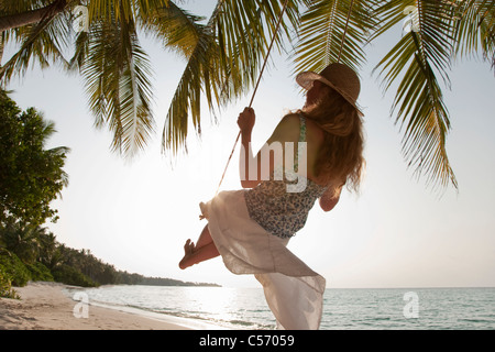 Seductive woman swinging on a swing on a tropical beach, on shores of