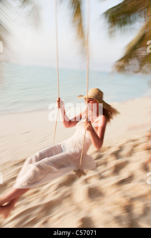 Seductive woman swinging on a swing on a tropical beach, on shores of