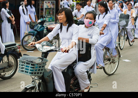 Students wearing white Ao Dai dress leaving school Stock Photo