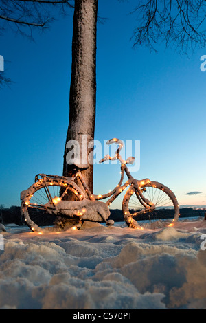The Netherlands, 's-Graveland, bicycle decorated with Christmas lights in snow. Dawn. Stock Photo