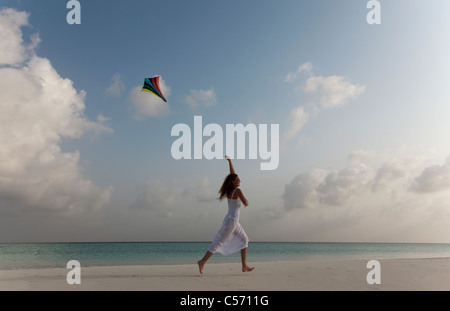 Woman flying a kite on tropical beach Stock Photo
