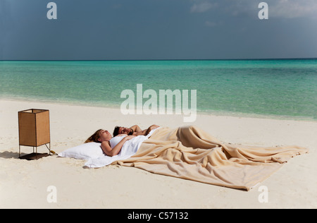 Couple sleeping in bed on beach Stock Photo